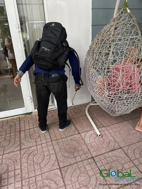 Kỹ thuật viên đeo bình phun xử lý côn trùng lối vào cửa hàng có ghế treo
