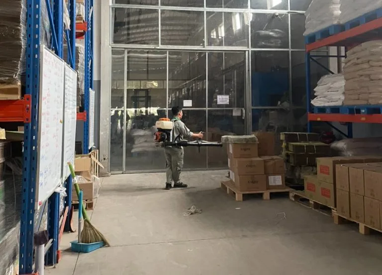 Kỹ thuật viên phun xử lý lối đi giữa các kệ hàng trong kho