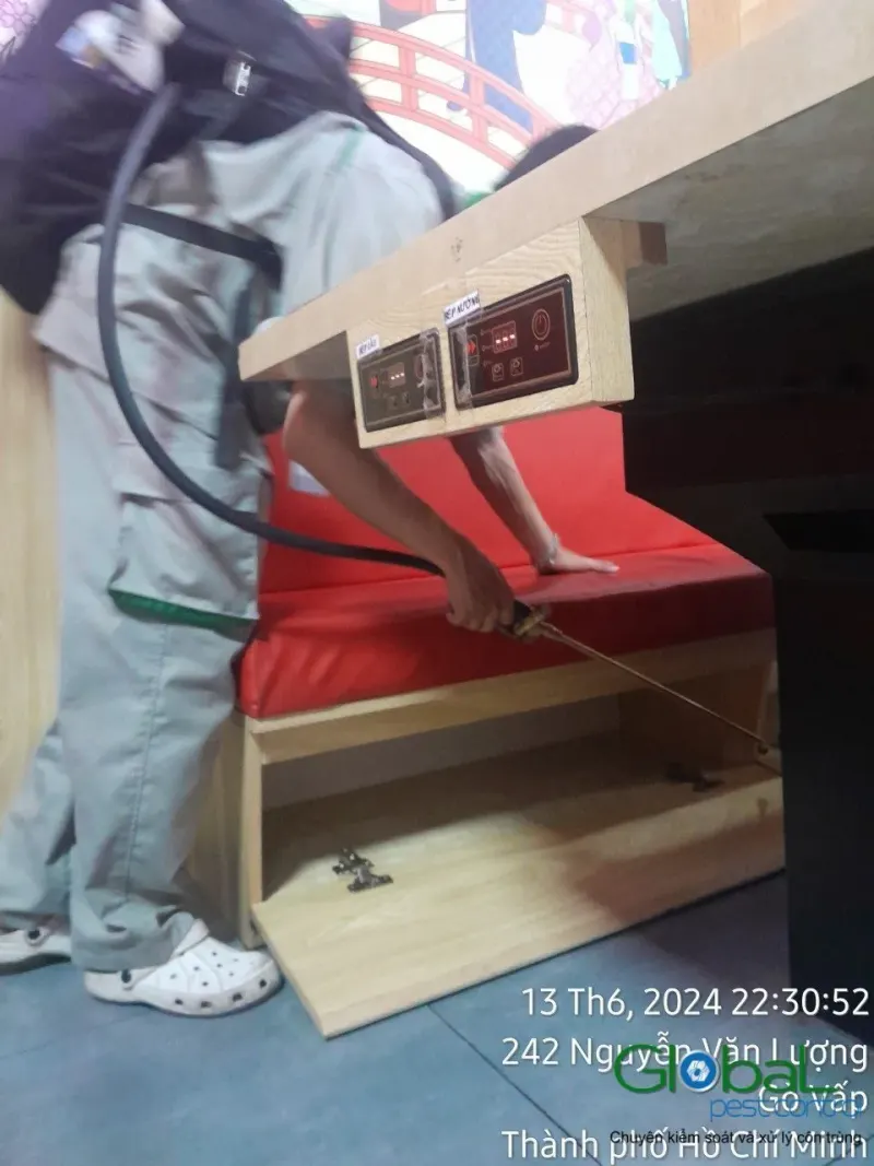 Kỹ thuật viên phun kẽ và gầm ghế sofa đỏ trong nhà hàng