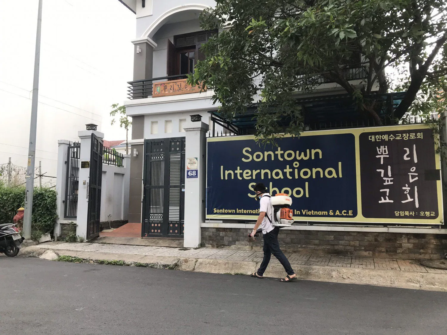 Kỹ thuật viên mang bình phun đi vào khuôn viên trường học