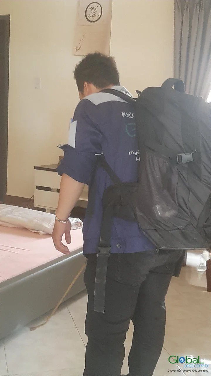 Kỹ thuật viên mang bình phun vào phòng ngủ đã dọn trống nệm
