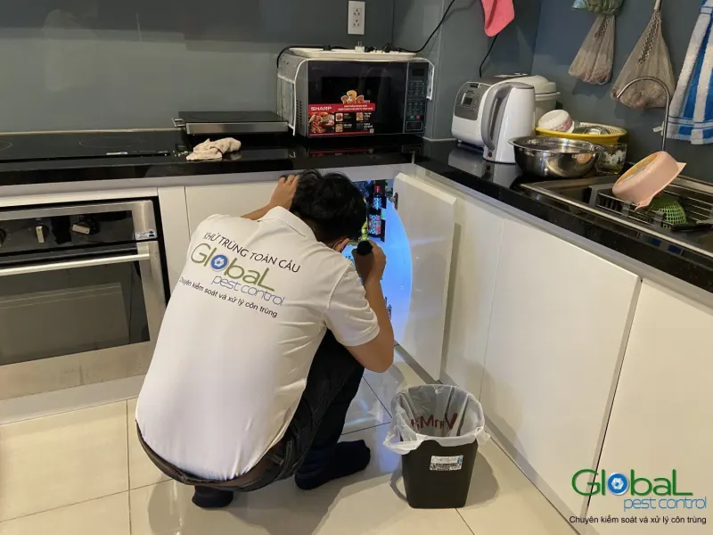 Kỹ thuật viên soi đèn kiểm tra gầm tủ bếp căn hộ