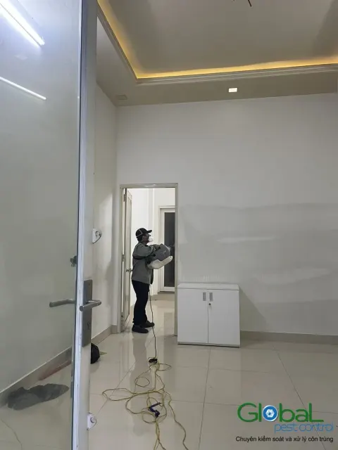 Kỹ thuật viên phun thuốc phòng trống có tủ gỗ trong nhà ở
