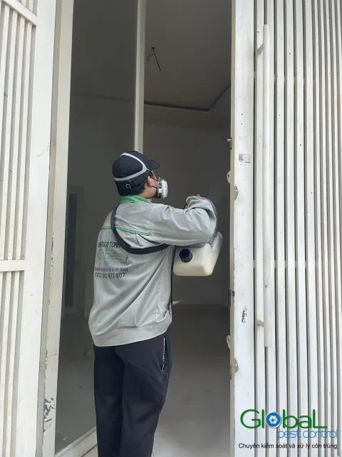 Kỹ thuật viên phun thuốc khe cửa sắt kéo trước nhà