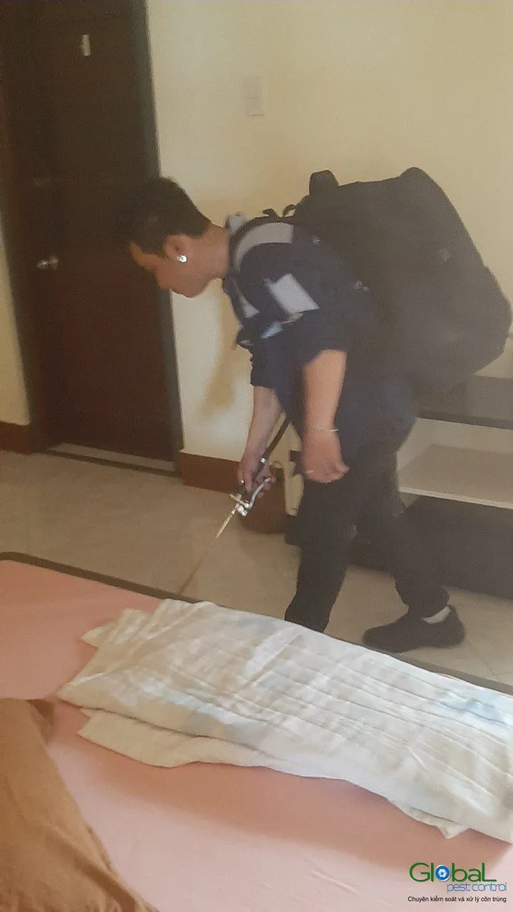 Kỹ thuật viên xịt tồn lưu dọc mép nệm và chân giường