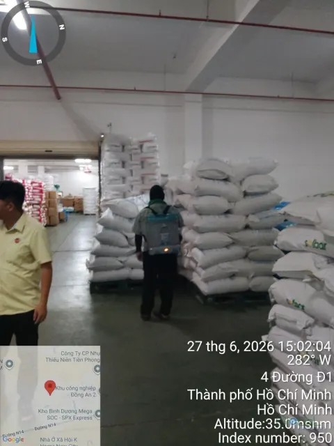Kỹ thuật viên phun thuốc quanh pallet bao nguyên liệu trong kho