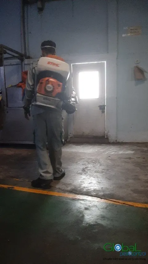 Kỹ thuật viên đeo máy phun động cơ phun thuốc lối đi nhà xưởng