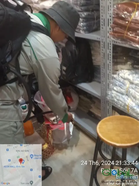 Kỹ thuật viên phun thuốc kẽ kệ hàng trong cửa hàng tạp hoá