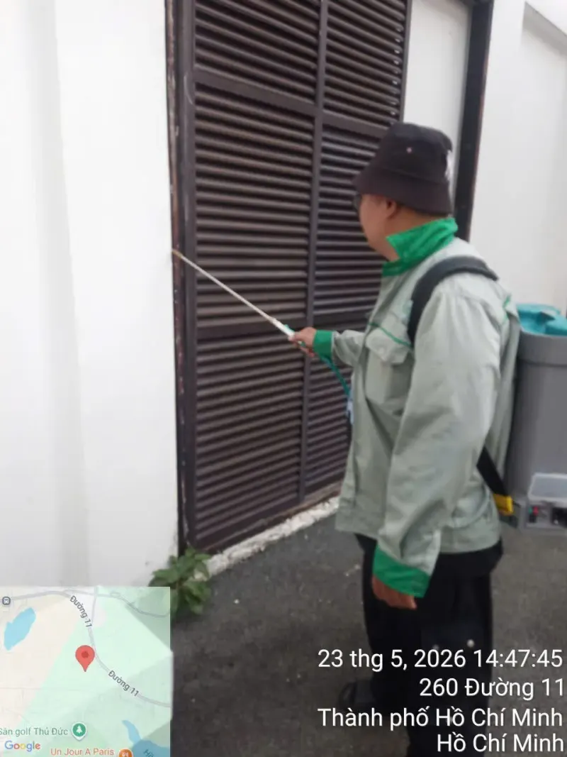 Kỹ thuật viên phun thuốc diệt muỗi cửa chớp gỗ ngoài nhà
