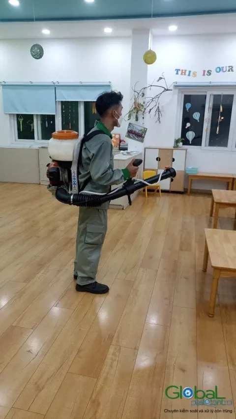 Kỹ thuật viên đeo máy phun động cơ phun lớp học sàn gỗ, phun định kỳ