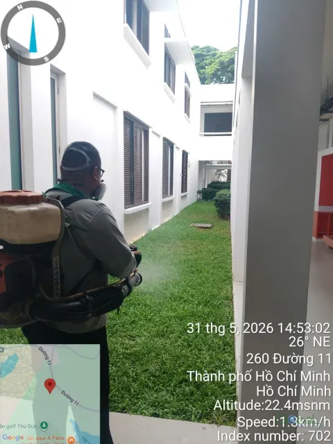 Kỹ thuật viên đeo máy phun động cơ phun thuốc diệt muỗi bãi cỏ trường học
