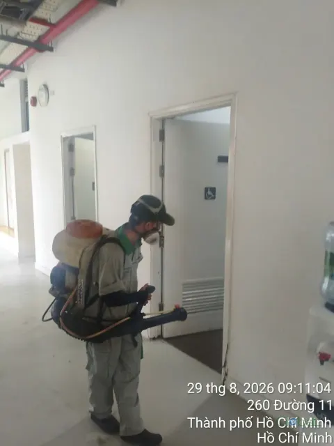 Kỹ thuật viên đeo máy phun động cơ phun thuốc hành lang dãy lớp học