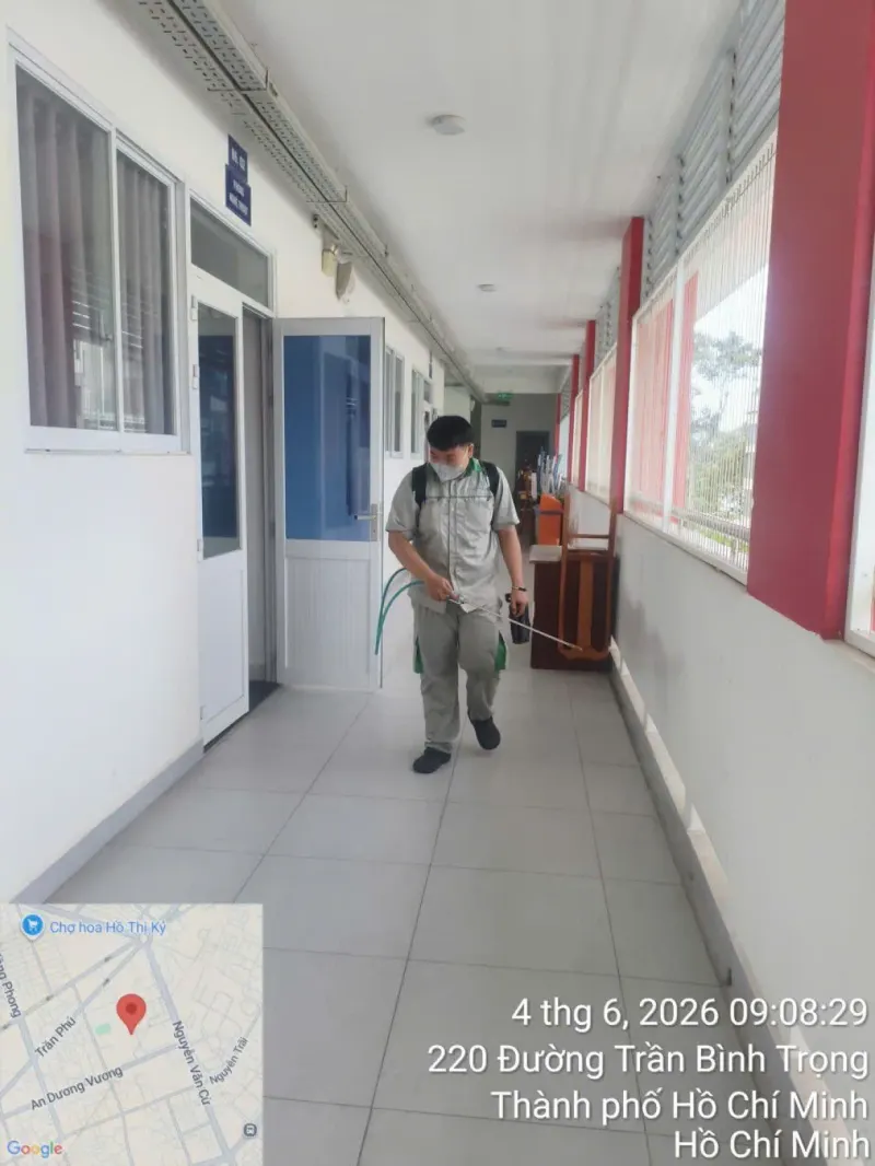 Kỹ thuật viên phun tồn lưu dọc chân tường hành lang một cơ sở đào tạo