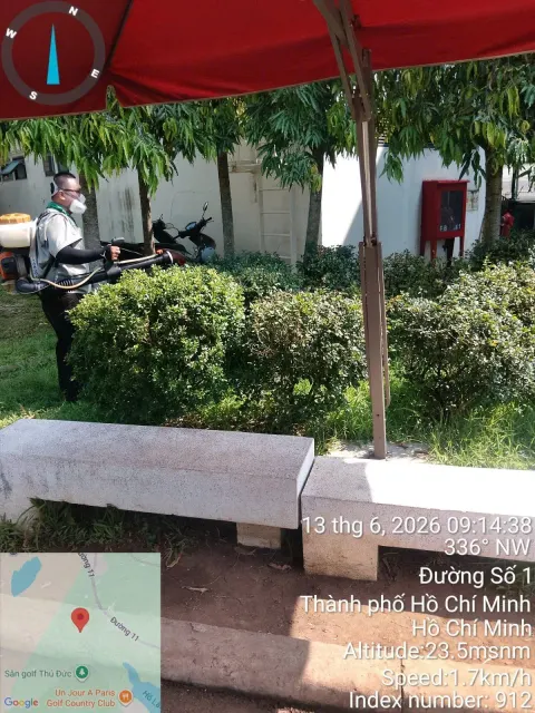 Kỹ thuật viên phun thuốc quanh bàn ghế ngoài trời dưới dù che