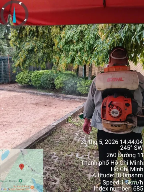 Kỹ thuật viên đeo máy phun động cơ phun thuốc diệt muỗi lối đi sân vườn