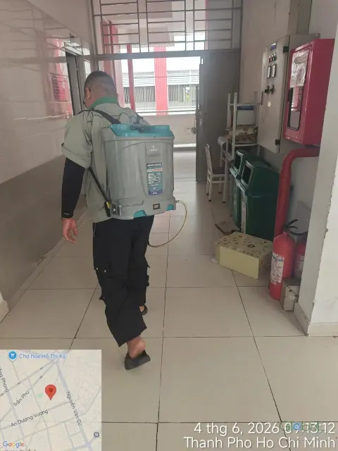 Kỹ thuật viên phun thuốc diệt côn trùng khu vực tủ chữa cháy hành lang trường