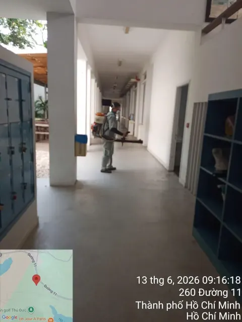 Kỹ thuật viên phun thuốc hành lang lớp học cạnh dãy tủ đựng đồ