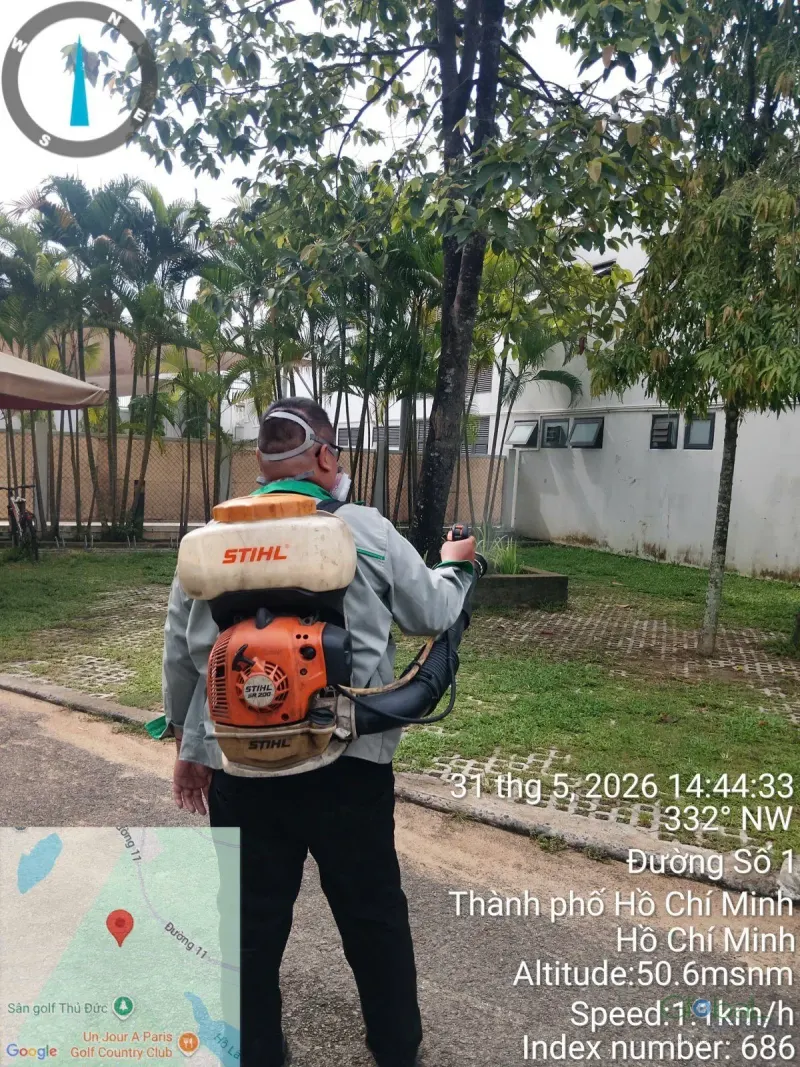 Kỹ thuật viên đeo máy phun phun thuốc sân cỏ trong khuôn viên nhà máy