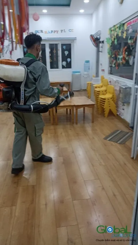 Kỹ thuật viên phun mù lạnh trong lớp mầm non có ghế nhựa