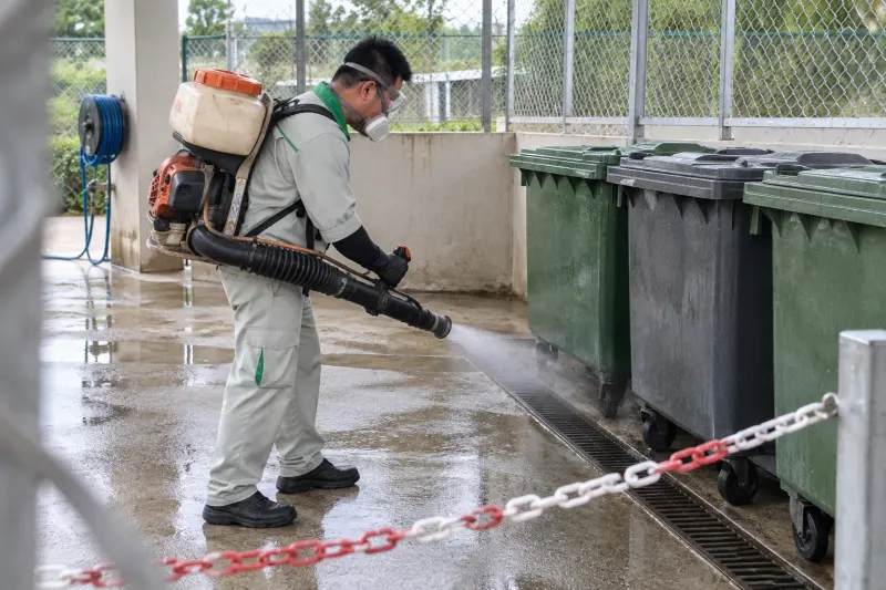 Kỹ thuật viên phun sương điểm tập kết rác cantin có thùng rác xanh