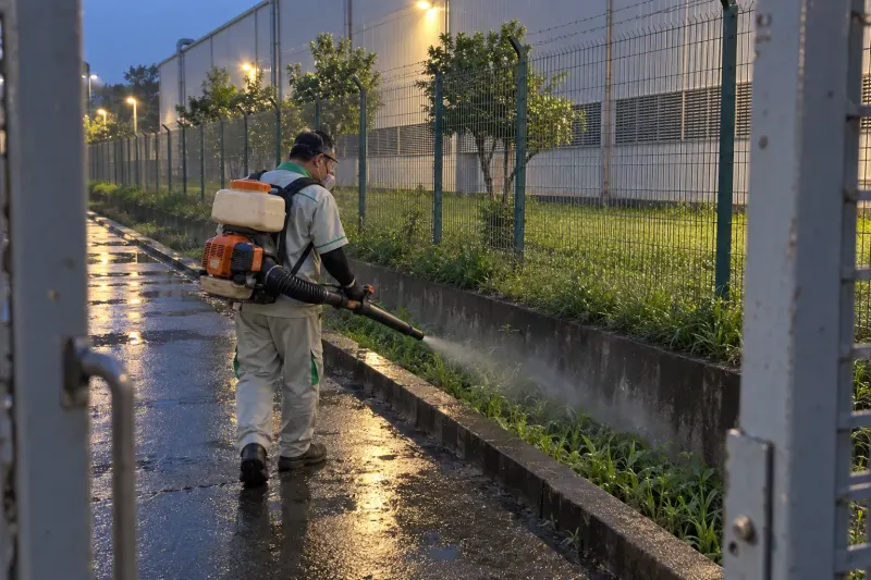 Kỹ thuật viên phun sương dọc hàng rào xưởng cao su buổi tối